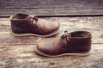 Brown stylish boots on wood background,  retro color