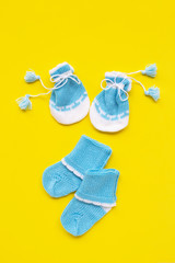 Baby gloves and socks on yellow background.
