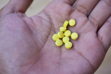 People holding Yellow pills placed on hand