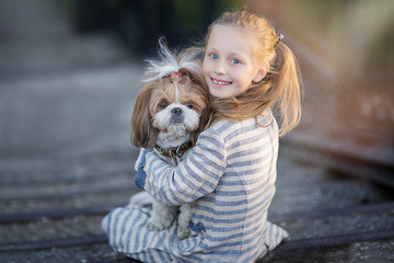 Little girl holding dog. Child with pet dog. Kid and animals friendship.