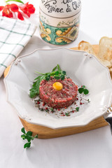 Steak Tartare with bread toasts and yolk on top on white table