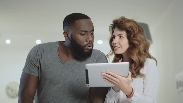 Young couple choosing photo at living room together.