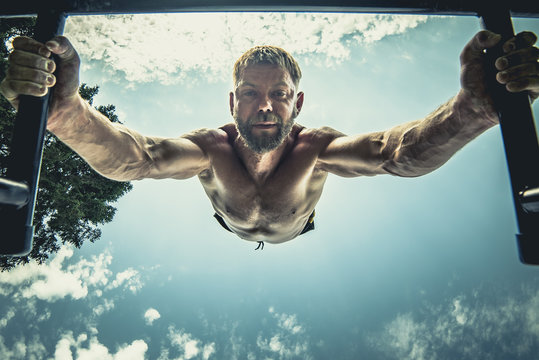 calisthenics hand stand fitness, sport, training and lifestyle concept - young man exercising on parallel bars outdoors