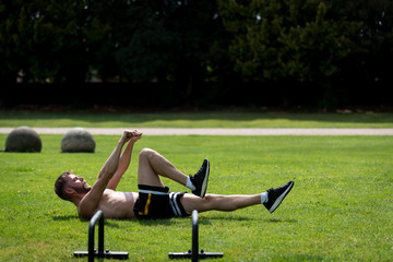 Man performing warm up before doing calisthenics fitness workout in an outdoor public park, UK