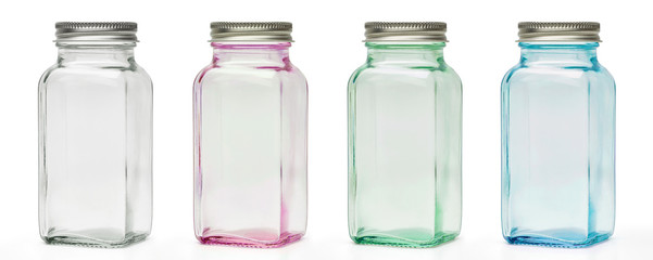 Clear pink, blue and green empty glass canisters or jars with silver cap isolated on white...