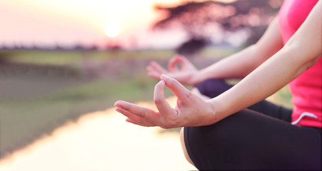 Woman practices yoga and meditates on the nature sunset background.