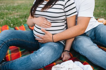 Image of pregnant couple. Husband touching his wife belly with hands. Pregnant woman outdoors