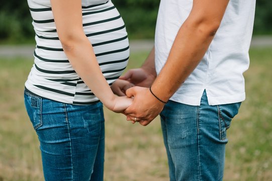 Image of pregnant couple. Husband touching his wife belly with hands. Pregnant woman outdoors