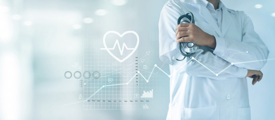 Male medicine doctor with stethoscope in hand standing confidently on hospital background