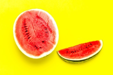 Half and pieces of ripe juicy red watermelon on bright yellow background. Flat lay, top view, copy space. Creative summer food concept