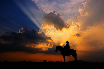 The silhouette of a cowboy on horseback at sunset on a  background - 281211893
