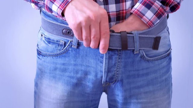 Man is scratching his dick and crotch putting his hand in jeans, hands closeup. Concept of sexually transmitted diseases.