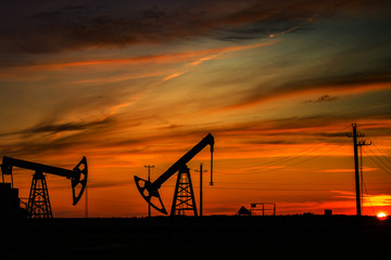 Pumping unit is working in oil field of the sunset. The contours of the oil rocking on the...