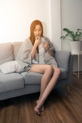 Asian young woman wrapped in a blanket and during illness and taking antipyretics..