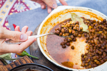 Black chickpeas. Kala chana masala with gravy. Woman hands holds, take spicy Indian traditional food.
