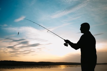 Fishing. spinning at sunset. Silhouette of a fisherman