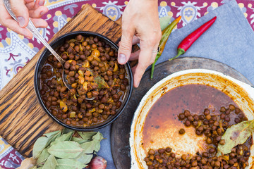 Black chickpeas. Kala chana masala with gravy. Woman hands holds, take spicy Indian traditional food.