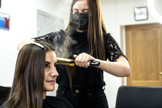 hairdresser makes hair lamination in a beauty salon for a girl with brunette hair. hair care concept.