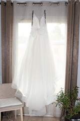 white wedding dress hanging on a window