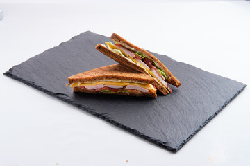 Club sandwich with ham, cheddar, cabbage and tomato isolated on white