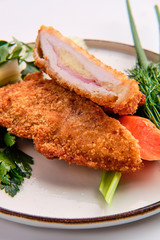 Baked cutlet stuffed with ham and cheese, covered with melted cheese isolated on white