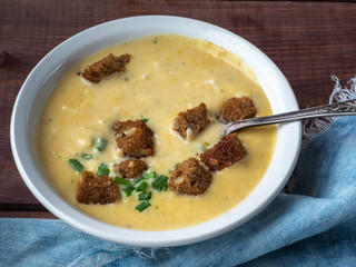Cheese soup puree with crackers of dark bread, a head of young garlic and a blue denim napkin on a...