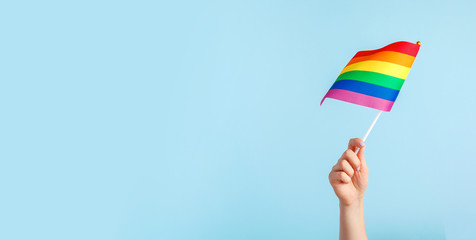 Gay flags in women's hand on grey background