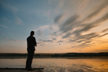 Fototapeta premium Fishing. spinning at sunset. Silhouette of a fisherman