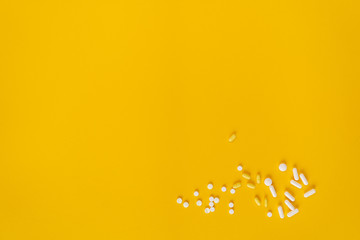 Tablets, pills and other medicine scattered in the right-down corner of the orange background. Treatment of illness, malaise. 