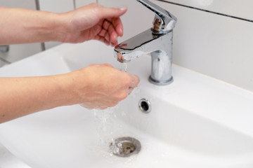 Women finish washing hands in the bathroom in the sink using purple color soap. Female hands under the tap and the water jet