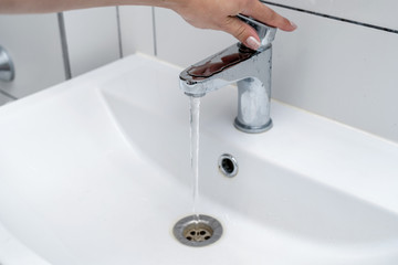 Washing hands in the bathroom in the sink. Women's hands close the tap with water