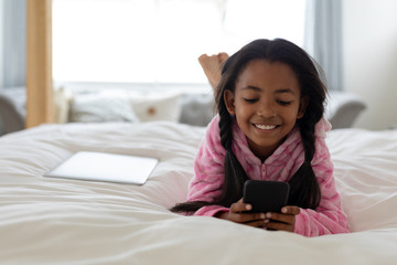 Girl using mobile phone on bed in bedroom at home