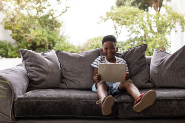 Boy using digital tablet in living room at home