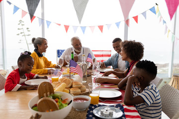 Multi-generation family sitting together for having meal on a dining table