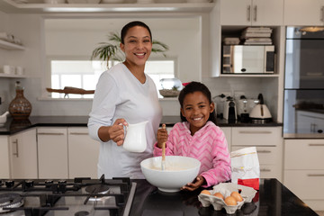 Mother and daughter preparing food on a worktop in kitchen at home