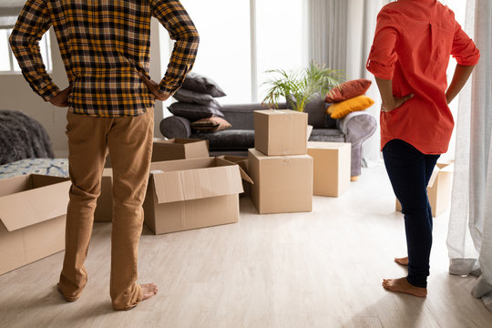 Couple Standing Together With Hands On Hip In Living Room At Home