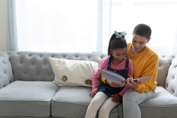 Mother and daughter reading a story book on a sofa in living room