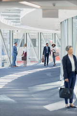 Diverse business people walking in corridor in modern office