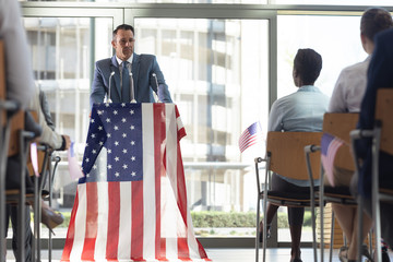 Group of diverse business people with flags listening mature businessman presentation