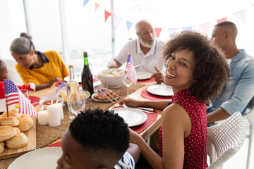 Multi-generation family sitting together for having meal on dining table