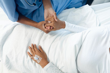 Female doctor consoling female patient in the ward at hospital