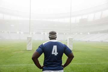 African american male rugby player standing with hands on hip in stadium