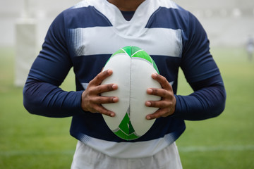African american male rugby player holding a rugby ball in stadium