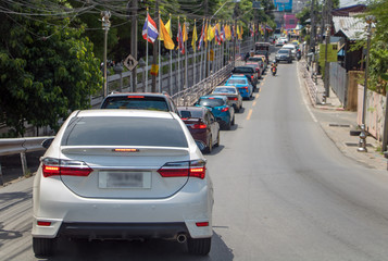 A convoy of cars beside a Buddhist temple on the feast day - Queen Suthida’s Birthday Anniversary, Thailand.