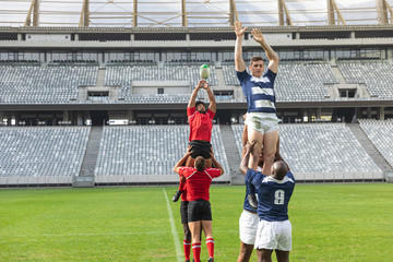 Male rugby players playing rugby match in stadium
