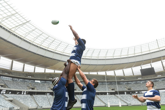 Group of diverse male rugby players playing rugby match in stadium - Powered by Adobe