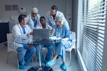 Medical team discussing over laptop on table at hospital