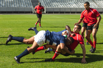 Male rugby players playing rugby match in stadium