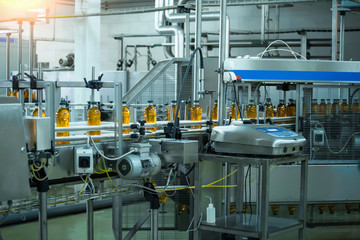 Automatic conveyor belt of production line of juice on beverage plant or factory, modern computerized industrial equipment. Fresh juice in plastic bottles