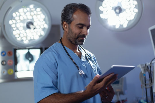 Mature male surgeon using digital tablet in operation room at hospital